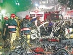Delhi Fire Services officials douse the flames while police personnel take stock of the situation at the explosion site on Monday night. (Sanjeev Verma/HT Photo)