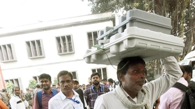 Officials escorted by security personnel carry electronic voting machines (EVMs) for polling stations in Patna, Bihar. (Santosh Kumar/HT Photo)