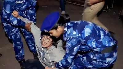Police personnel detain a protester during the protest against rising air pollution at India Gate, in New Delhi on Sunday. (ANI Video Grab)
