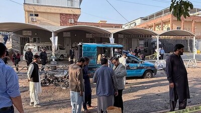 Security officials examine a damaged vehicle at the site following a suicide bombing outside the gates of a district court, in Islamabad, (AP)