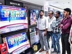 People watch exit polls on TV sets at a showroom after the second phase of the Bihar assembly elections, in Patna on Tuesday. 