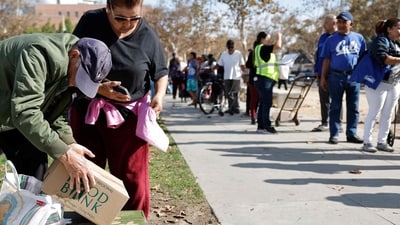 LOS ANGELES, CALIFORNIA - NOVEMBER 11: People prepare to depart (L) after receiving free food boxes as others wait in line at a large-scale food distribution, in response to the federal government shutdown and SNAP/CalFresh food benefits delays, on November 11, 2025 in Los Angeles, California. (Photo by MARIO TAMA / GETTY IMAGES NORTH AMERICA / Getty Images via AFP) (Getty Images via AFP) LOS ANGELES, CALIFORNIA - NOVEMBER 11: People prepare to depart (L) after receiving free food boxes as others wait in line at a large-scale food distribution, in response to the federal government shutdown and SNAP/CalFresh food benefits delays, on November 11, 2025 in Los Angeles, California. (Photo by MARIO TAMA / GETTY IMAGES NORTH AMERICA / Getty Images via AFP) (Getty Images via AFP)