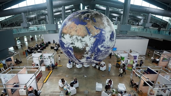 Attendees sit under a globe in a lobby at the side events pavilions at the COP30 U.N. Climate Summit, Tuesday, Nov. 11, 2025, in Belem, Brazil. (AP Photo/Fernando Llano) (AP)