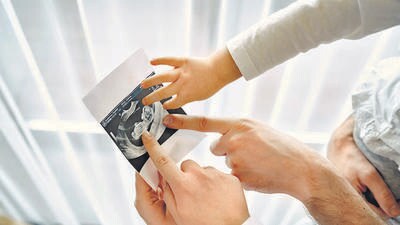 Mom dad and daughter watching photos. Family in light clothes. Family expecting a baby.