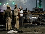 Police personnel stand beside charred vehicles at the blast site after an explosion near the Red Fort in the old quarters of Delhi.