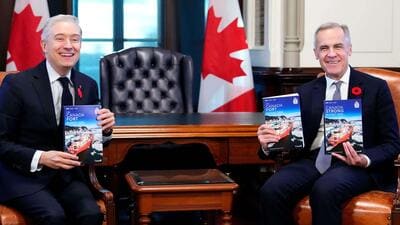 Prime Minister Mark Carney (right) and Minister of Finance and National Revenue Francois-Philippe Champagne hold up copies of the budget as they pose for a photograph before the tabling of the federal budget on Parliament Hill in Ottawa, on November 4. (AP)