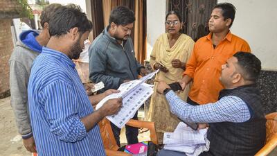 A Booth Level Officer explains the details of enumeration forms to citizens during the Special Intensive Revision of electoral rolls. (PTI) A Booth Level Officer explains the details of enumeration forms to citizens during the Special Intensive Revision of electoral rolls. (PTI)