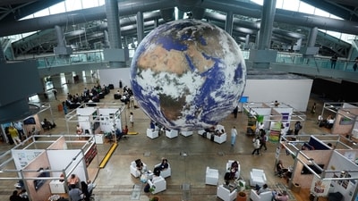 Attendees sit under a globe in a lobby at the side events pavilions at the COP30 U.N. Climate Summit, Tuesday, Nov. 11, 2025, in Belem, Brazil. (AP Photo/Fernando Llano) (AP)