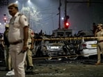 Police inspect charred vehicles as they codorn off the blast site after an explosion near the Red Fort in Delhi.
