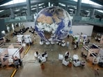 Attendees sit under a globe in a lobby at the side events pavilions at the COP30 U.N. Climate Summit, Tuesday, Nov. 11, 2025, in Belem, Brazil. (AP Photo/Fernando Llano)