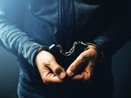 Arrested computer hacker and cyber criminal with handcuffs, close up of hands (Getty Images/iStockphoto)