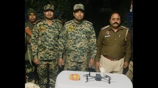 The BSF team with the drone and packet containing the drug in Kamal Wala village of Ferozepur on Saturday. (HT Photo)