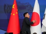 FILE PHOTO: A staff member organises flags of China, Japan and Korea before the start of the 28th ASEAN Plus Three Summit in Kuala Lumpur, Malaysia.