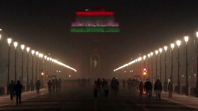 People walking at the India Gate in Delhi on Monday night. (ANI)