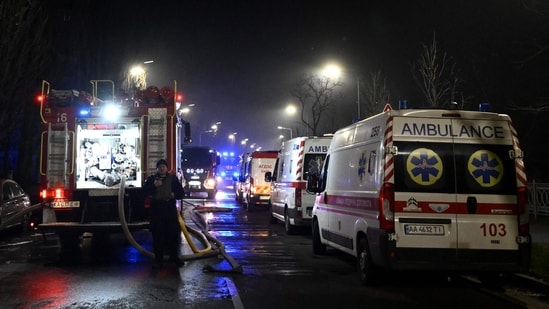 A Ukrainian law enforcement officer stands next to ambulances and a fire truck parked at the site of an air attack in Kyiv on November 25, 202. (AFP)