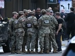 National Guard soldiers huddle around law enforcement officers while receiving information after a shooting in downtown Washington, DC, on November 26, 2025. National Guard soldiers huddle around law enforcement officers while receiving information after a shooting in downtown Washington, DC, on November 26, 2025.
