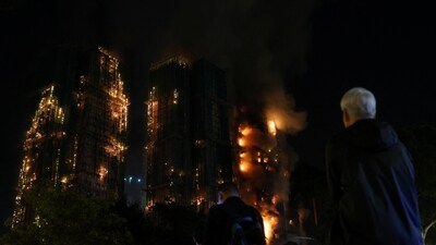 People watch as flames burn bamboo scaffolding across multiple buildings. (REUTERS)