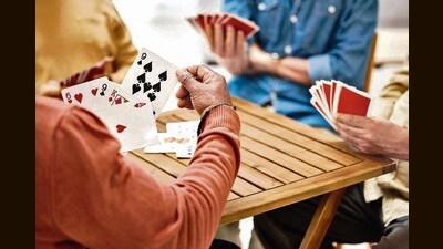 Senior friends, hands or playing card games on wooden table in fun activity, social bonding or gathering. Group of elderly men having fun with cards for poker game enjoying play time together at home (Shutterstock) Senior friends, hands or playing card games on wooden table in fun activity, social bonding or gathering. Group of elderly men having fun with cards for poker game enjoying play time together at home (Shutterstock)