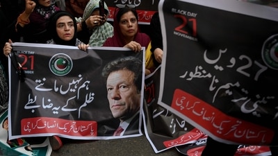 Pakistan Tehreek-e-Insaf (PTI) party supporters carry a poster of their leader and former Prime Minister Imran Khan, during a protest against in Karachi on November 21 (AFP/File)