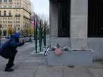 A pedestrian photographs a makeshift memorial outside of the Farragut West Metro Station a day after two National Guard members were shot in Washington, D.C.