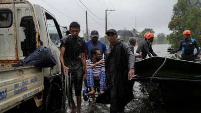 Members of the Sri Lankan Army along with villagers help a person in a wheelchair to a safe location from flooded streets following heavy rainfall in Wellampitiya, Sri Lanka, November 28, 2025. (REUTERS)