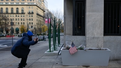 A pedestrian photographs a makeshift memorial outside of the Farragut West Metro Station a day after two National Guard members were shot in Washington, D.C. (REUTERS)