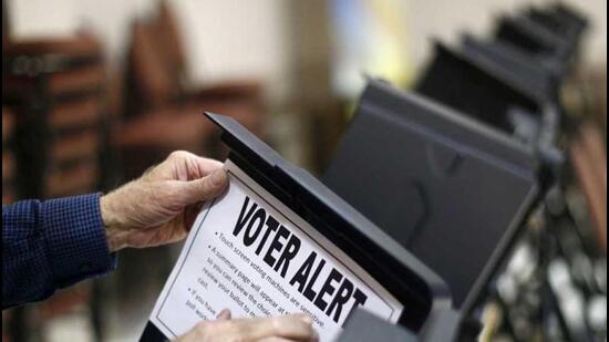 Poll worker Bill Bryant tapes up a sign on a voting machine warning voters of the sensitivity of the touch screen during the US presidential election in Pineville, North Carolina. Reuters photo