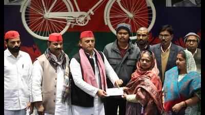 SP chief Akhilesh Yadav handing over a cheque of  ₹2-lakh ex gratia to the dependents of a deceased BLO, in Lucknow on Saturday. (HT Photo)