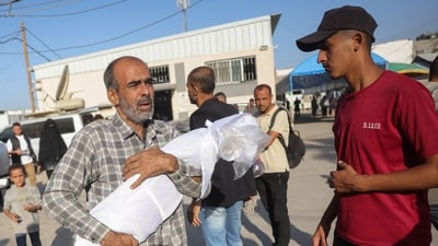 A Palestinian man carries the draped body of a child killed in Israeli strikes the previous day on the central Gaza Strip, outside the Shuhada al-Aqsa hospital ahead of a burial ceremony for the victims in Deir al-Balah on October 20, 2025. (AFP) A Palestinian man carries the draped body of a child killed in Israeli strikes the previous day on the central Gaza Strip, outside the Shuhada al-Aqsa hospital ahead of a burial ceremony for the victims in Deir al-Balah on October 20, 2025. (AFP)