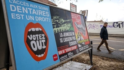 A person walks past referendum posters of political parties and associations as Swiss voters are casting ballots to decide whether women, like men, must do national service in the military, civil protection teams or in other forms, in Geneva, Switzerland. (AP)
