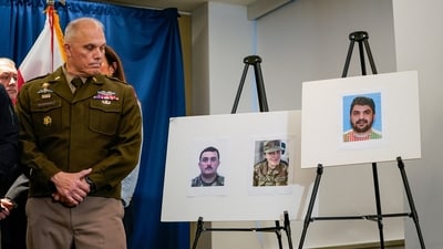 An officer looks towards pictures of two National Guard members who were shot in Washington on November 26, along with a picture of the suspect, Afghan national Rahmanullah Lakanwal. (Reuters Photo)