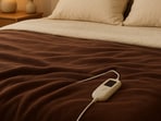 Soft folds and warm tones create a snug scene with an electric heated blanket ready to cosy up a winter bed.(AI generated)