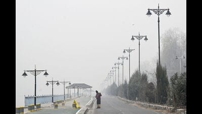A man sweeps a road along the banks of the Dal Lake on a cold foggy afternoon in Srinagar on Monday. (AFP)