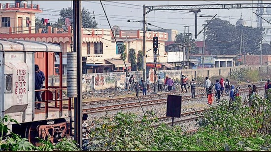 People crossing the tracks to scale the wall erected by the railways. (Gurpreet Singh/HT)