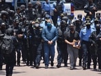 Former Honduras president Juan Orlando Hernandez (centre) is escorted by police officers in his country before his extradition to the US on April 21, 2022. He was convicted of helping to smuggle 400 tonnes of cocaine into the US.  Hernandez was released from a West Virginia, US, prison on Monday and was "once again a free man", his wife announced on social media on December 2. 