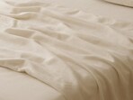 Soft folds rest across a tidy bed as fitted bedsheets create a neat look that feels warm, simple and ready for the evening.(AI generated)
