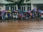 Students walk past the waterlogged portion of their school amid rain due to Cyclone Ditwah, in Chennai, Monday.
