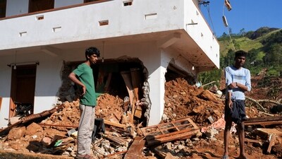 People stand next to debris near a damaged house after landslides caused by heavy rainfall following Cyclone Ditwah in Kandy, Sri Lanka, December 2, 2025. (REUTERS)