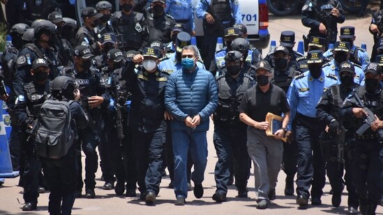 Former Honduras president Juan Orlando Hernandez (centre) is escorted by police officers in his country before his extradition to the US on April 21, 2022. He was convicted of helping to smuggle 400 tonnes of cocaine into the US. Hernandez was released from a West Virginia, US, prison on Monday and was "once again a free man", his wife announced on social media on December 2. (AFP)