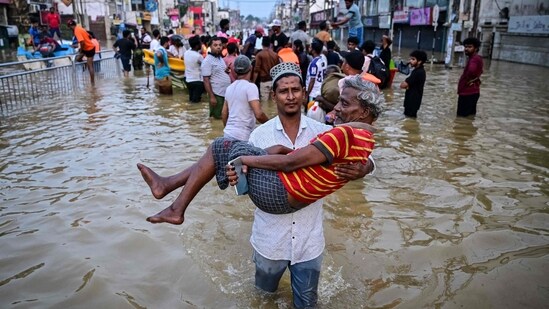 A youth carries an elderly man as they wade through a flooded street after heavy rainfall in Wellampitiya on the outskirts of Colombo. The floods and landslides were triggered by Cyclone Ditwah. (AFP)