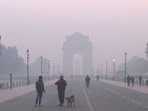 People walk along Kartavya Path, covered in a layer of smog as the AQI nears 400, in New Delhi.