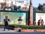 People walk past a hoarding installed outside Hyderabad House to welcome Russia's President Vladimir Putin to India on his visit, in New Delhi on Thursday. (ANI Photo)