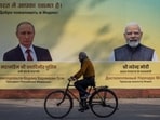 A man cycles past a hoarding with images of Russian President Vladimir Putin and Indian Prime Minister Narendra Modi ahead of Putin's visit, in New Delhi,