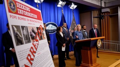 A poster reads "ARRESTED" in bold letters as Attorney General Pam Bondi, FBI Director Kash Patel, and FBI Deputy Director Dan Bongino, and others speak during a news conference. (Getty Images via AFP)