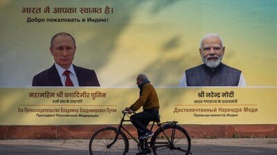 A man cycles past a hoarding with images of Russian President Vladimir Putin and Indian Prime Minister Narendra Modi ahead of Putin's visit, in New Delhi, (REUTERS)