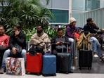 Travellers sit after their flight was cancelled by IndiGo Airlines at the Indira Gandhi International Airport in Delhi, India, December 5, 2025. 