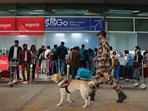 A police personnel walks with a sniffer dog as stranded passengers crowd the IndiGo airlines ticketing desk at the Lal Bahadur Shastri International Airport in Varanasi on December 6, 2025. 