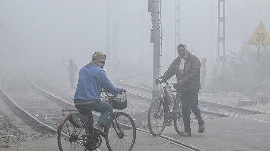 Commuters cross railway tracks on a foggy winter morning in Nadia, West Bengal, on Friday. (PTI)