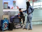 A passenger with her son wait at Terminal 1 of the Indira Gandhi International Airport as IndiGo’s flight disruptions continue nationwide, in New Delhi on Sunday. 