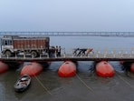 Labourers carry iron plates to construct a temporary road over pontoon bridge across the Ganga in Prayagraj on Sunday. (AP) Labourers carry iron plates to construct a temporary road over pontoon bridge across the Ganga in Prayagraj on Sunday. (AP)